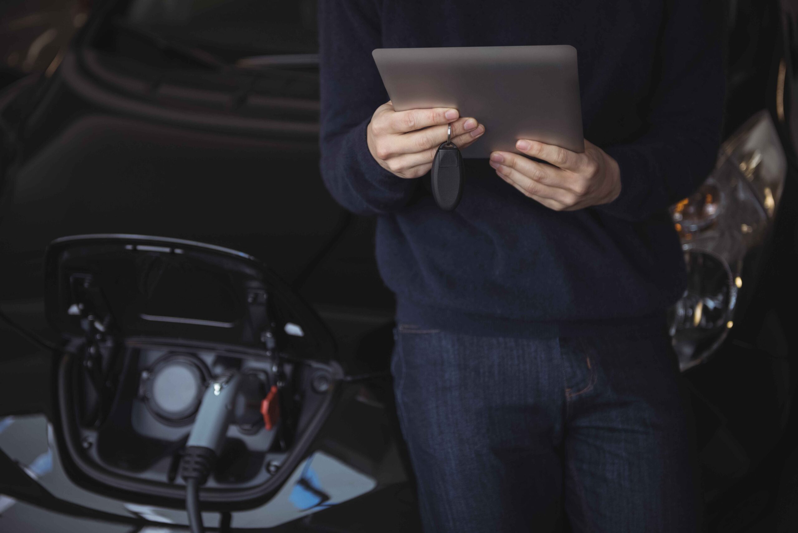 mid-section-man-using-digital-tablet-while-charging-electric-car_11zon