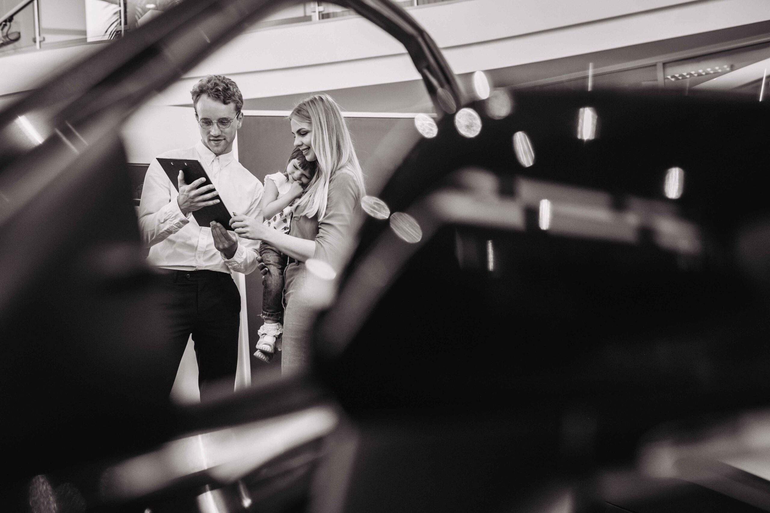 mother-with-daughter-talking-sales-person-car-showroom_11zon